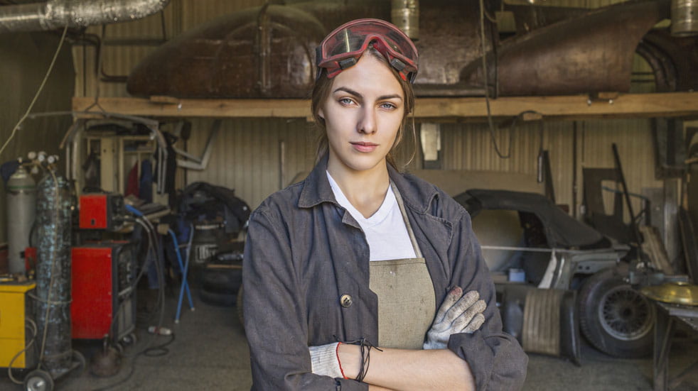 Restoring a classic car; woman in garage